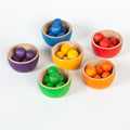 Set of colorful wooden toy bowls with small colourful wooden balls on a white background