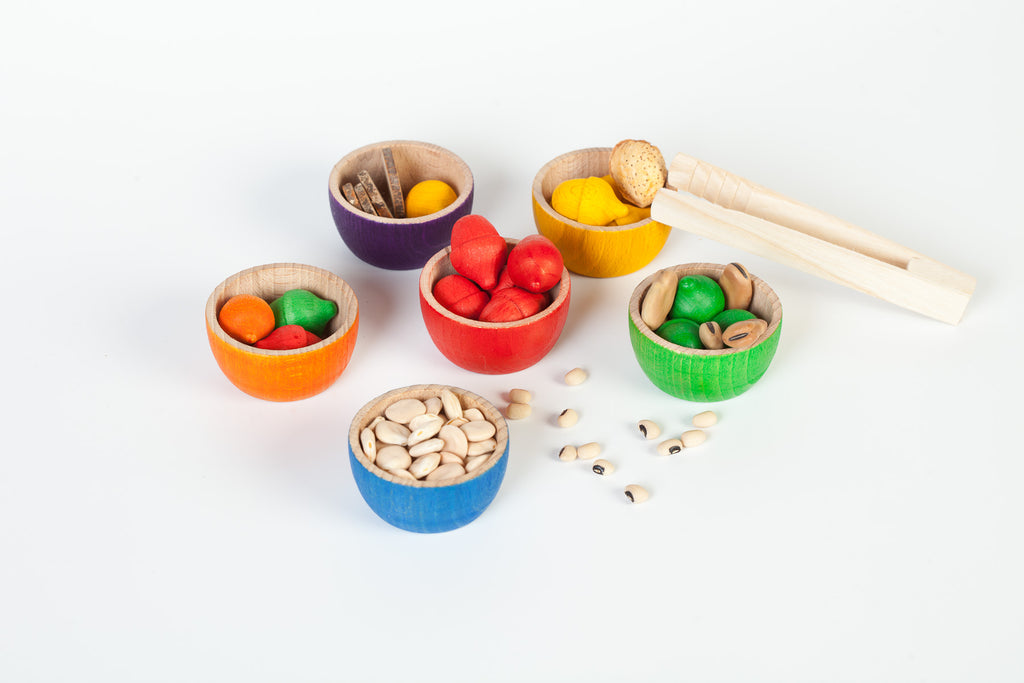 Colourful wooden toy bowls filled with colourful wooden acorns and other natural materials 