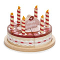 Wooden toy chocolate birthday cake with six candles and cake topper which says happy birthday.  The cake is divided into six pieces and presented on a wooden plate.